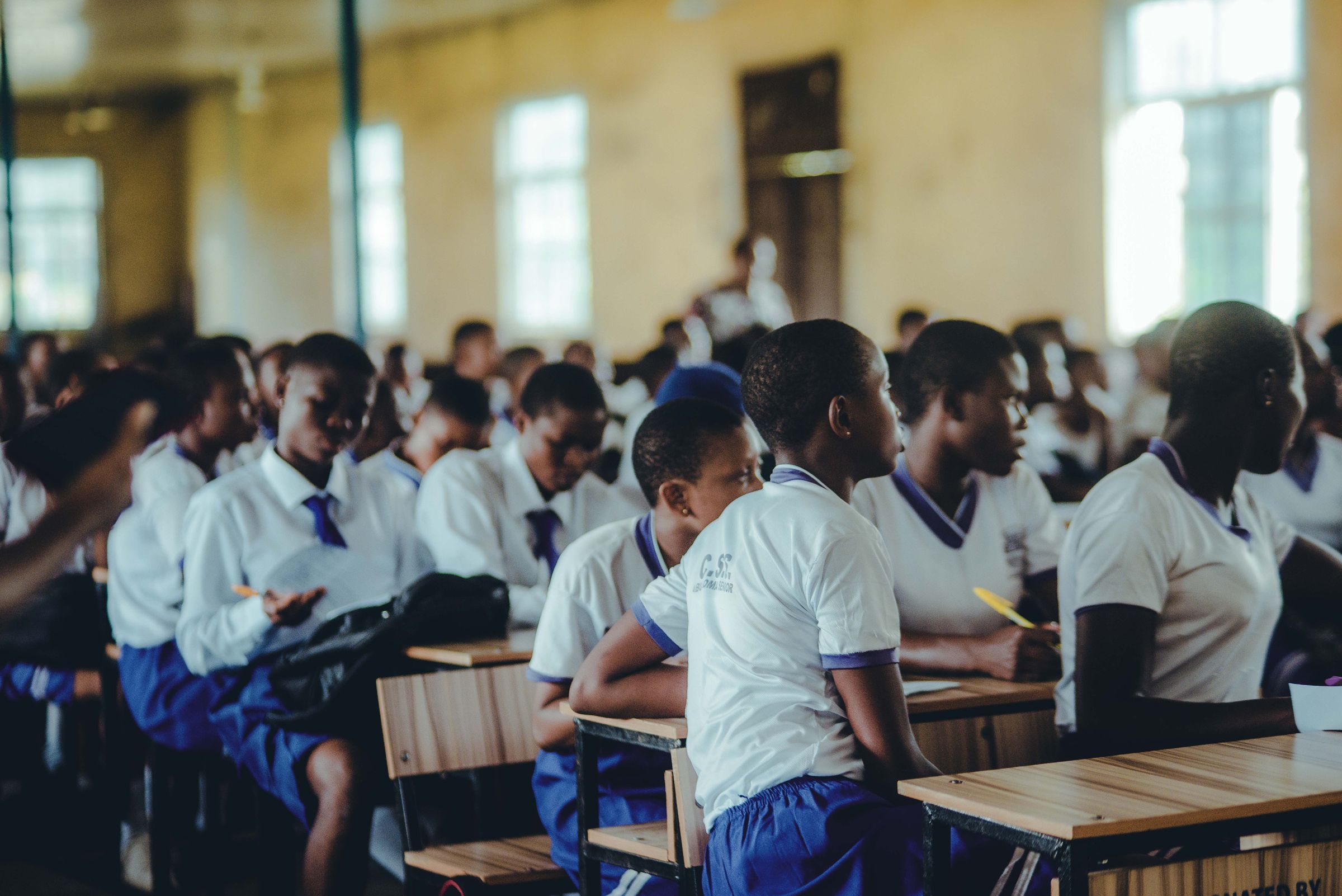 A full hall of secondary school students at their desks, learning