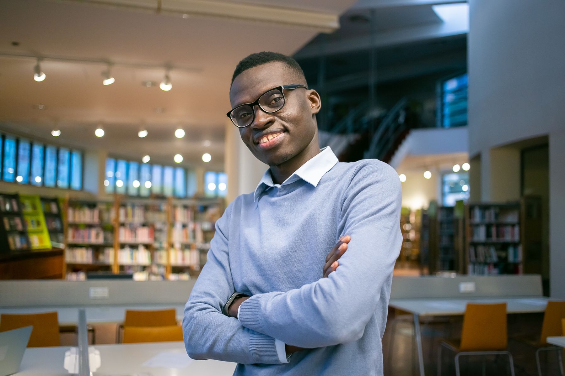 A confident young man standing in a library