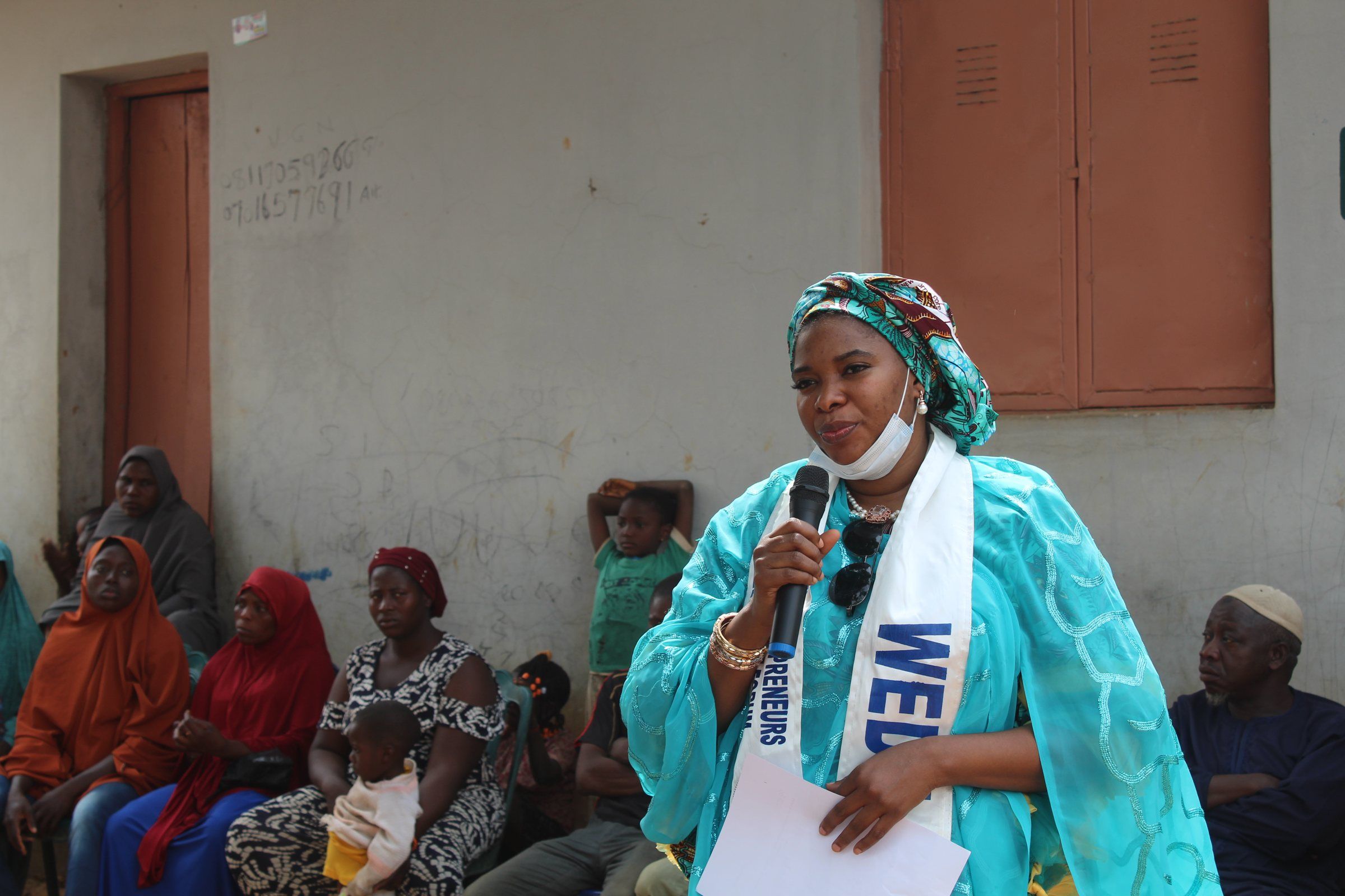 A woman addressing a community gathering with a microphone
