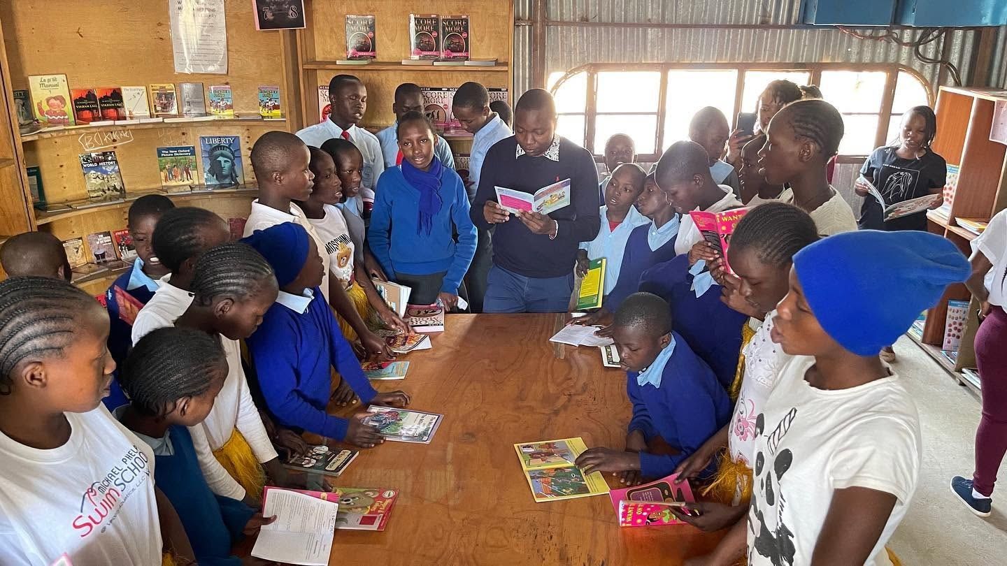 Students in school uniform reading books around a library table