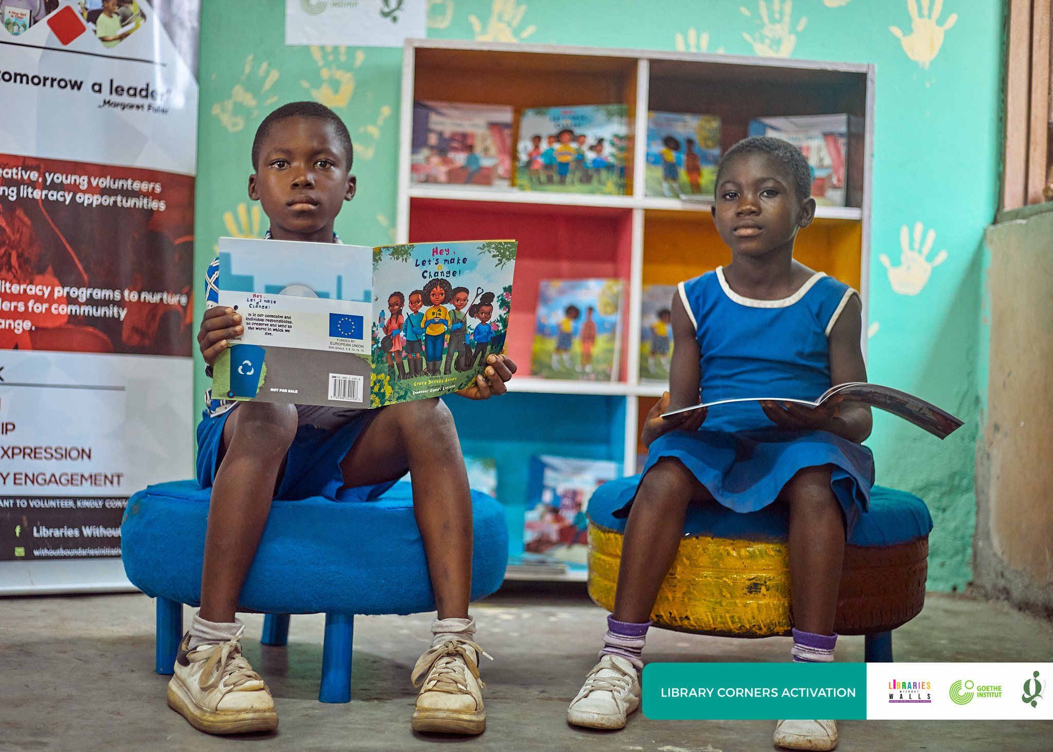 Two pupils reading on painted tyre seats in a newly set-up library corner