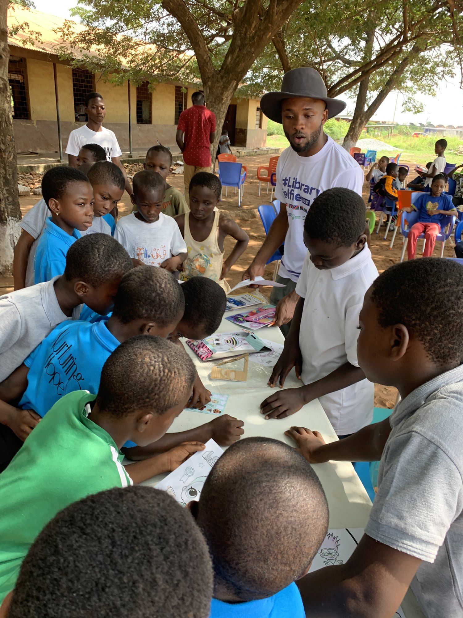 A volunteer guiding a child through a drawing activity outdoors