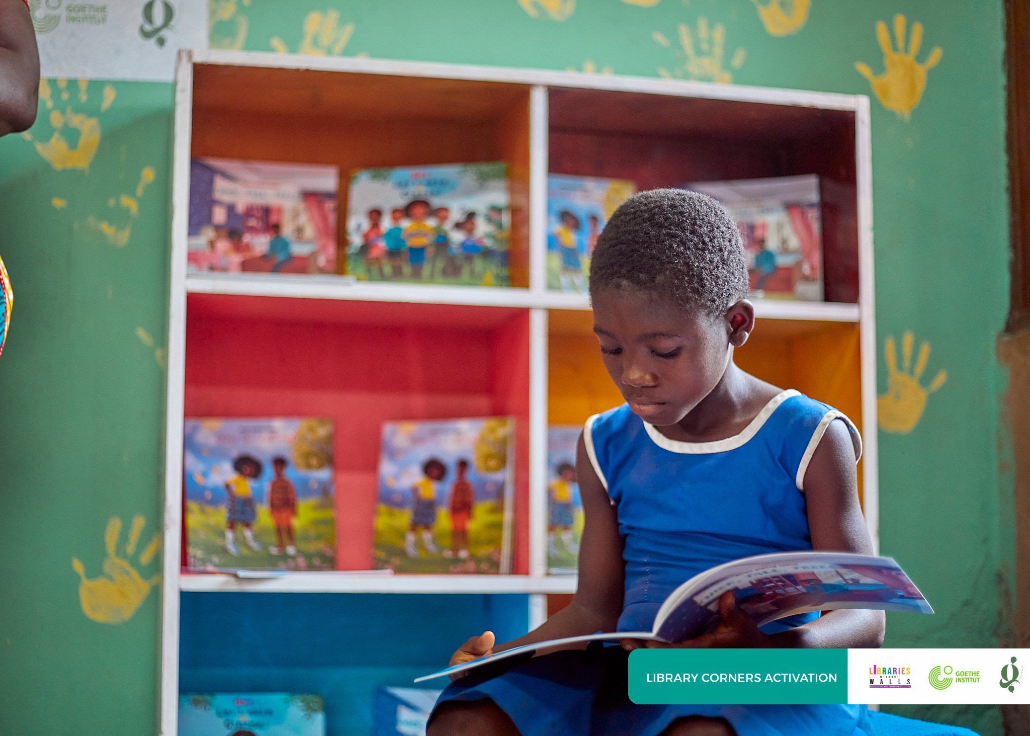 A schoolgirl reading a picture book in front of a colourful library corner bookshelf