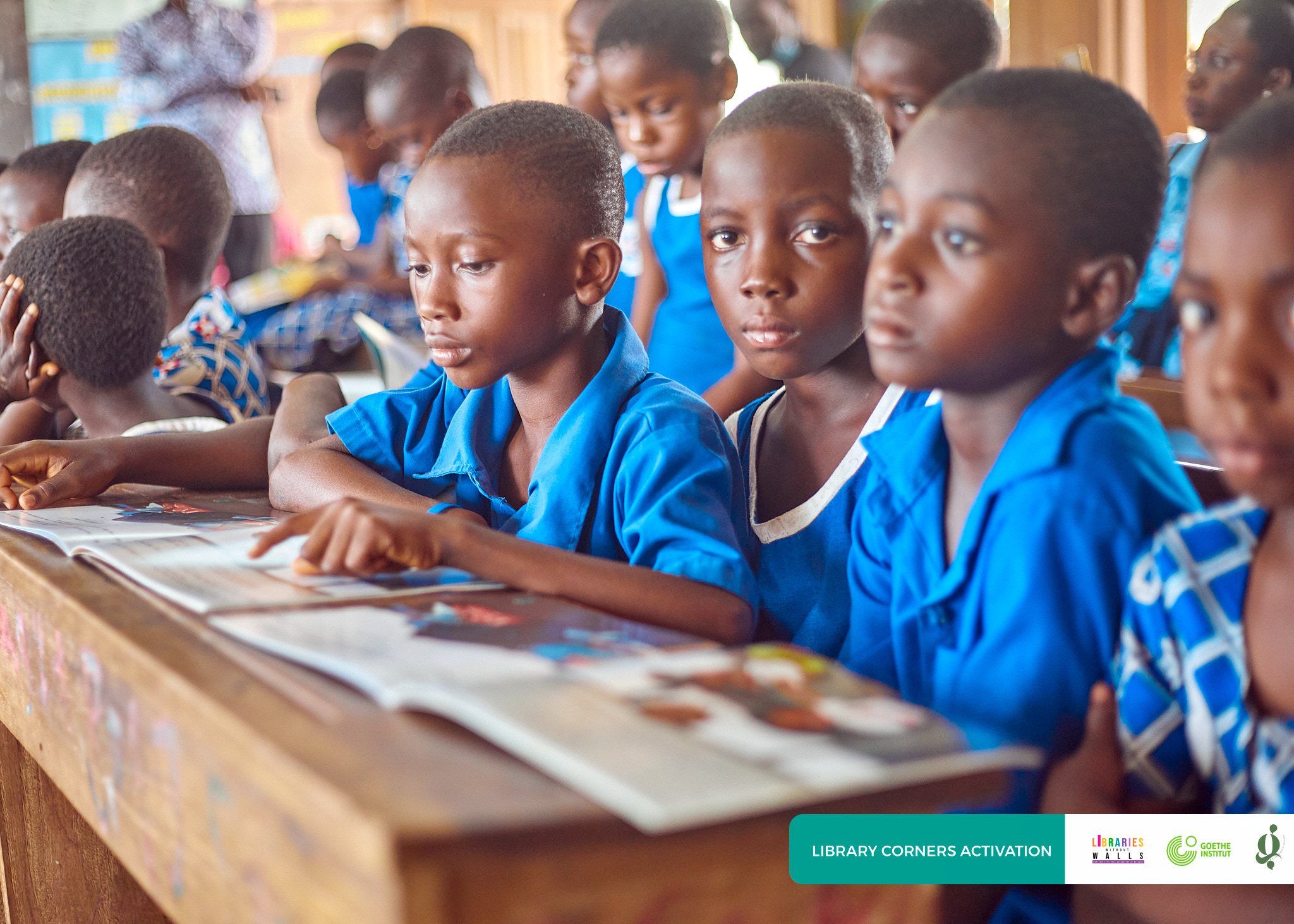 Students in school uniform reading books together at their desks