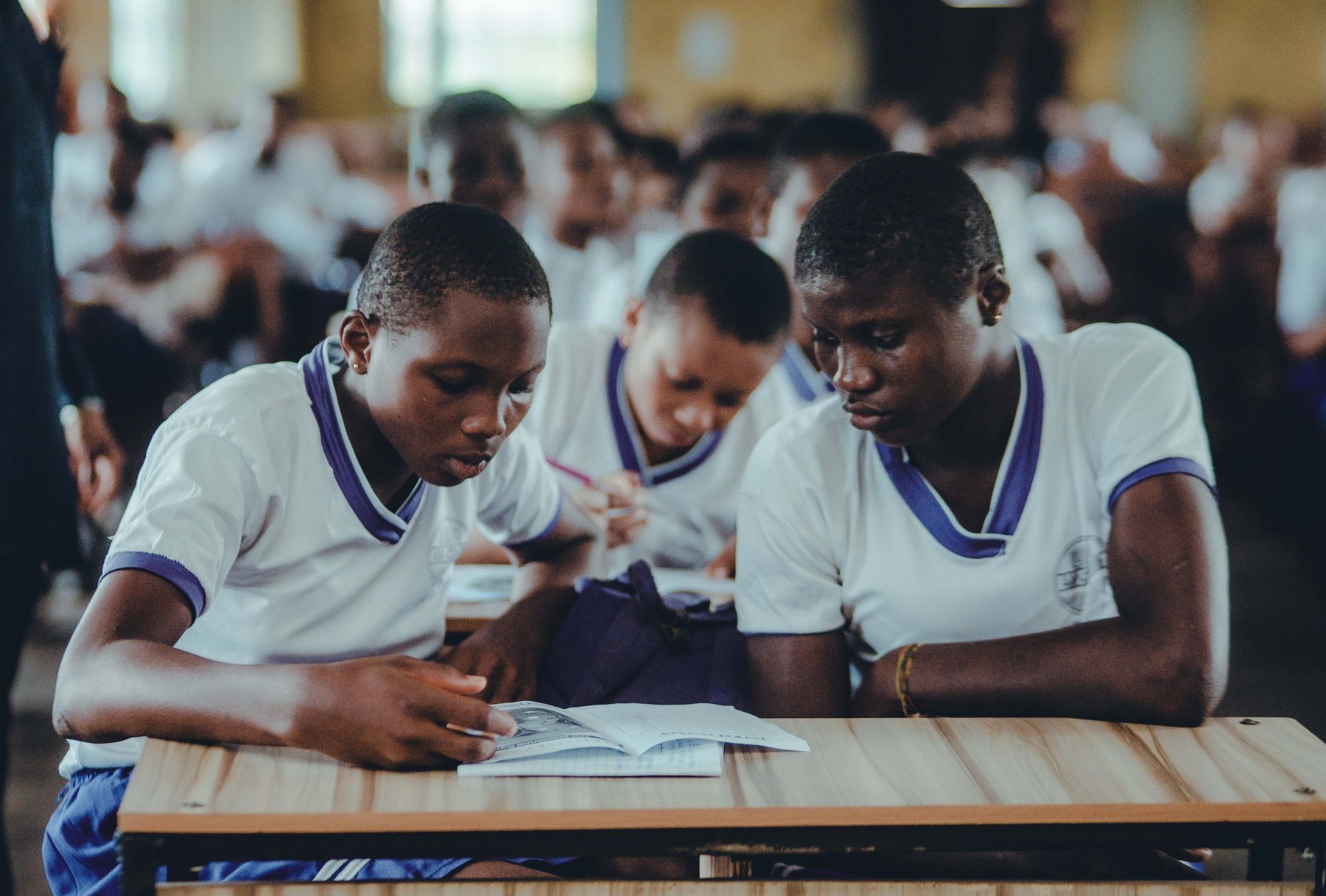 Two students in school uniform reading and taking notes together